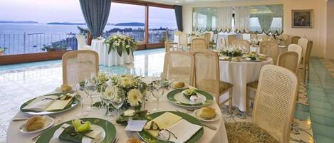 A dining area with round tables set for a meal, featuring green plates and white tablecloths.