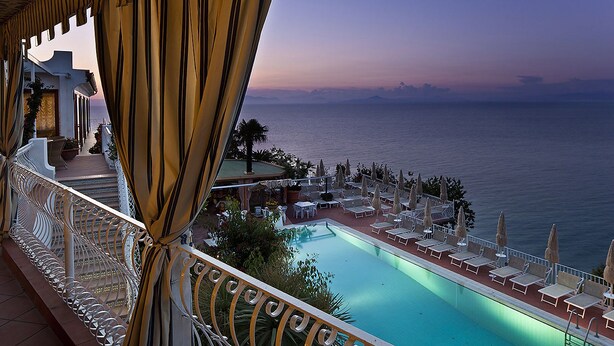A poolside view with a clear view of the sea, a lounge area with sun loungers, and a staircase leading to an upper level. - Le Querce Resort Sea Thermae & SPA (Ischia)