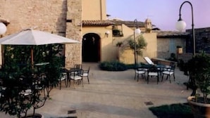 Un patio al aire libre con paredes de piedra, mobiliario exterior y plantas en macetas.