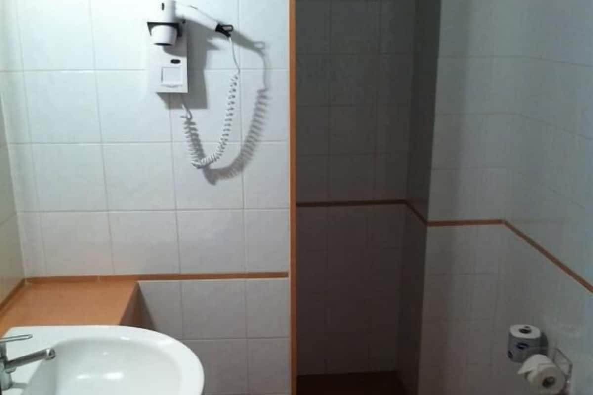 A small bathroom with a sink, toilet, and shower.