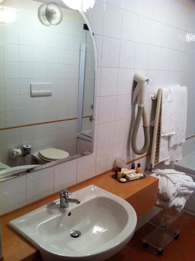 Ein Badezimmer mit Waschbecken, Toilette, Spiegel und Handtuchhalter.