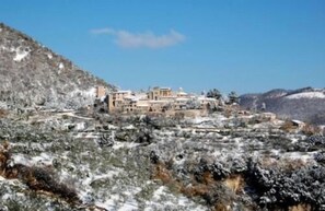 A mountainous village with traditional stone buildings, some with flat roofs, surrounded by snow-covered terrain and sparse vegetation. - Hotel Palazzo Bocci (Spello)