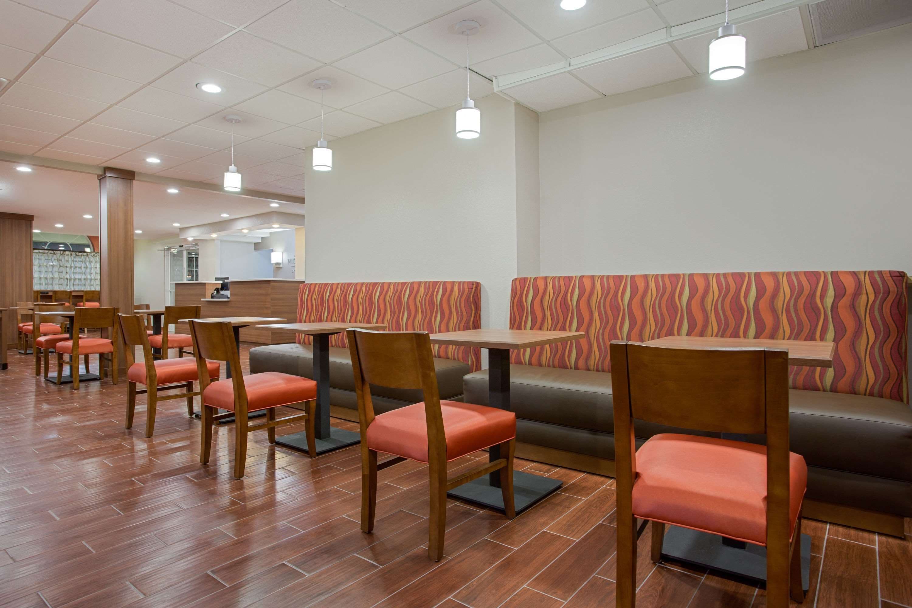 A restaurant with wooden chairs and tables, a patterned sofa, and a tiled floor.