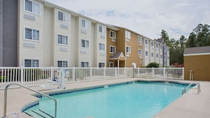 A swimming pool with a white fence, a lifeguard chair, and a sign indicating no diving. - Microtel Inn & Suites by Wyndham Walterboro (Walterboro)