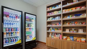 Two cold drink vending machines and a snack shelf stocked with various brands. - Microtel Inn & Suites by Wyndham Walterboro (Walterboro)