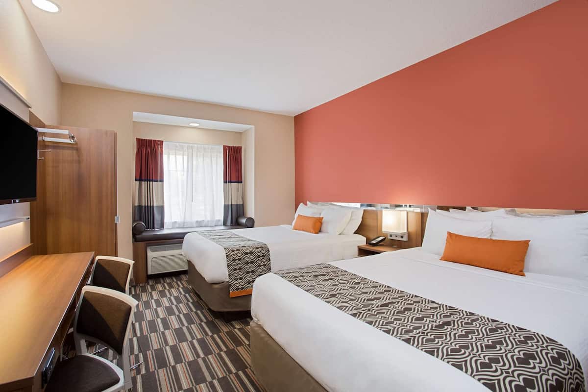 A hotel room with two beds, a desk, and a chair.