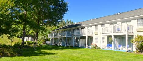 A two-story hotel with a covered outdoor seating area and a well-maintained lawn.