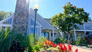 A building with a stone facade, large windows, and a well-maintained garden with colorful flowers. - The Lodge At Jackson Village (Jackson)