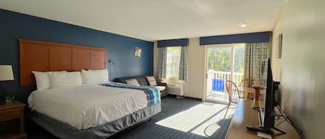 Una habitación de hotel con una cama grande, un escritorio con ordenador, una silla y una ventana con cortinas.