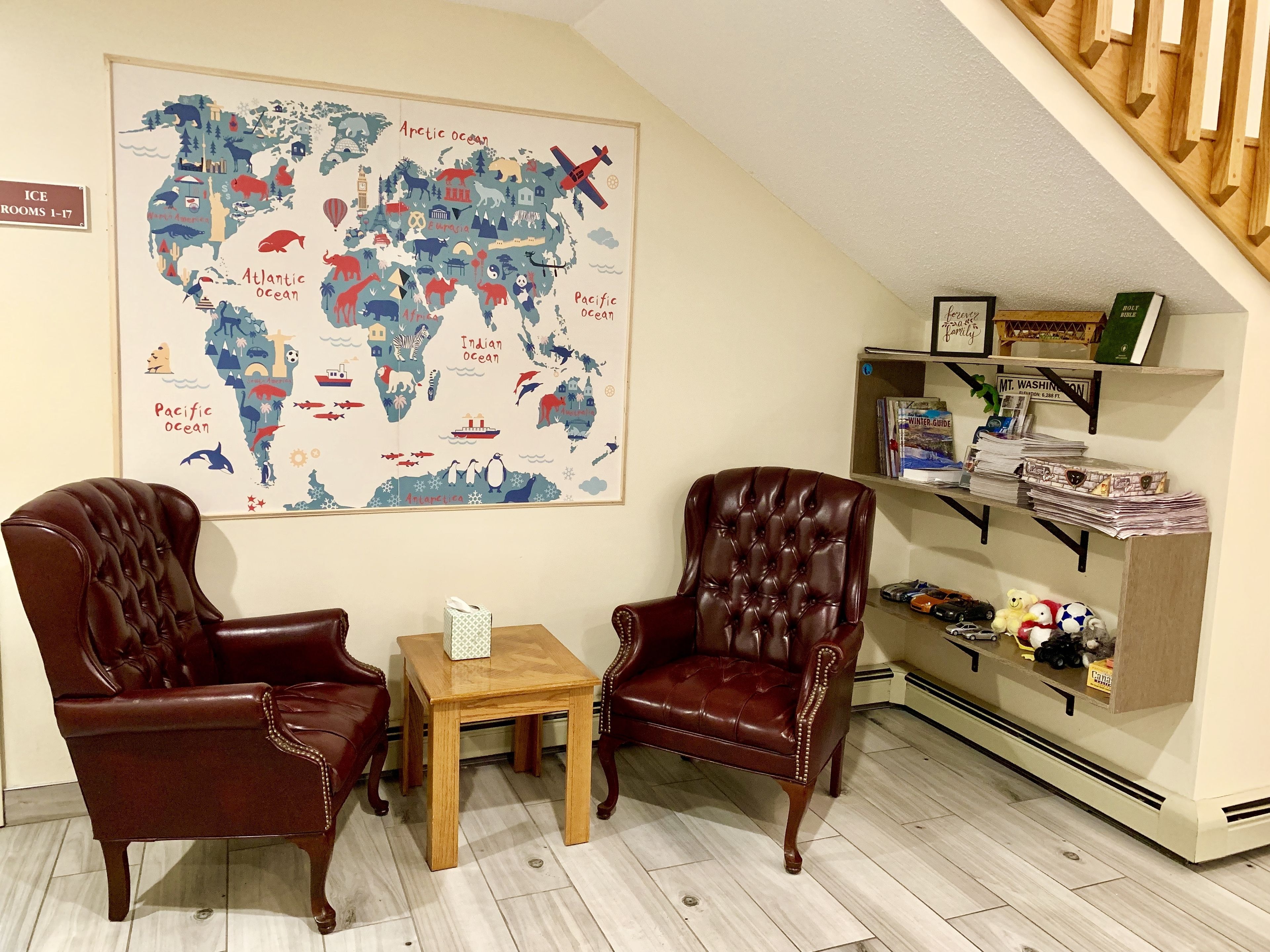 A cozy room with two leather armchairs, a small wooden table, and a world map on the wall.