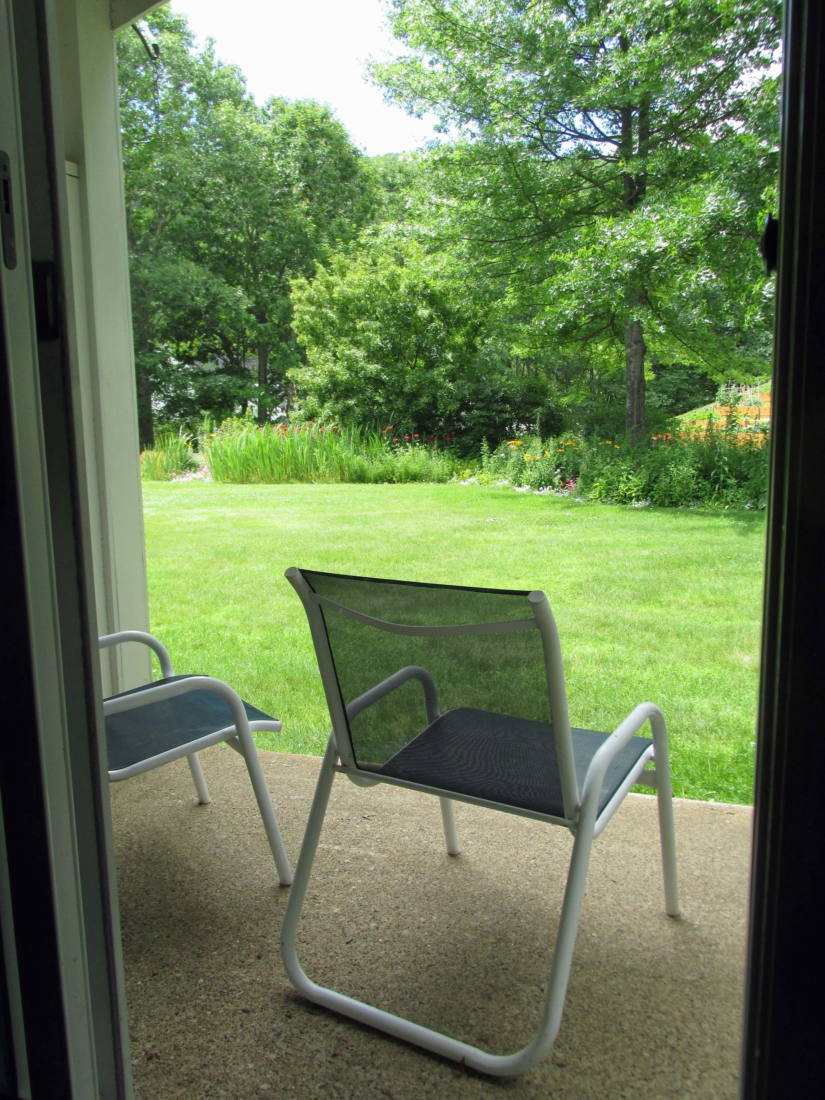 Eine Terrasse mit zwei Stühlen, die auf einen üppigen Garten blicken.