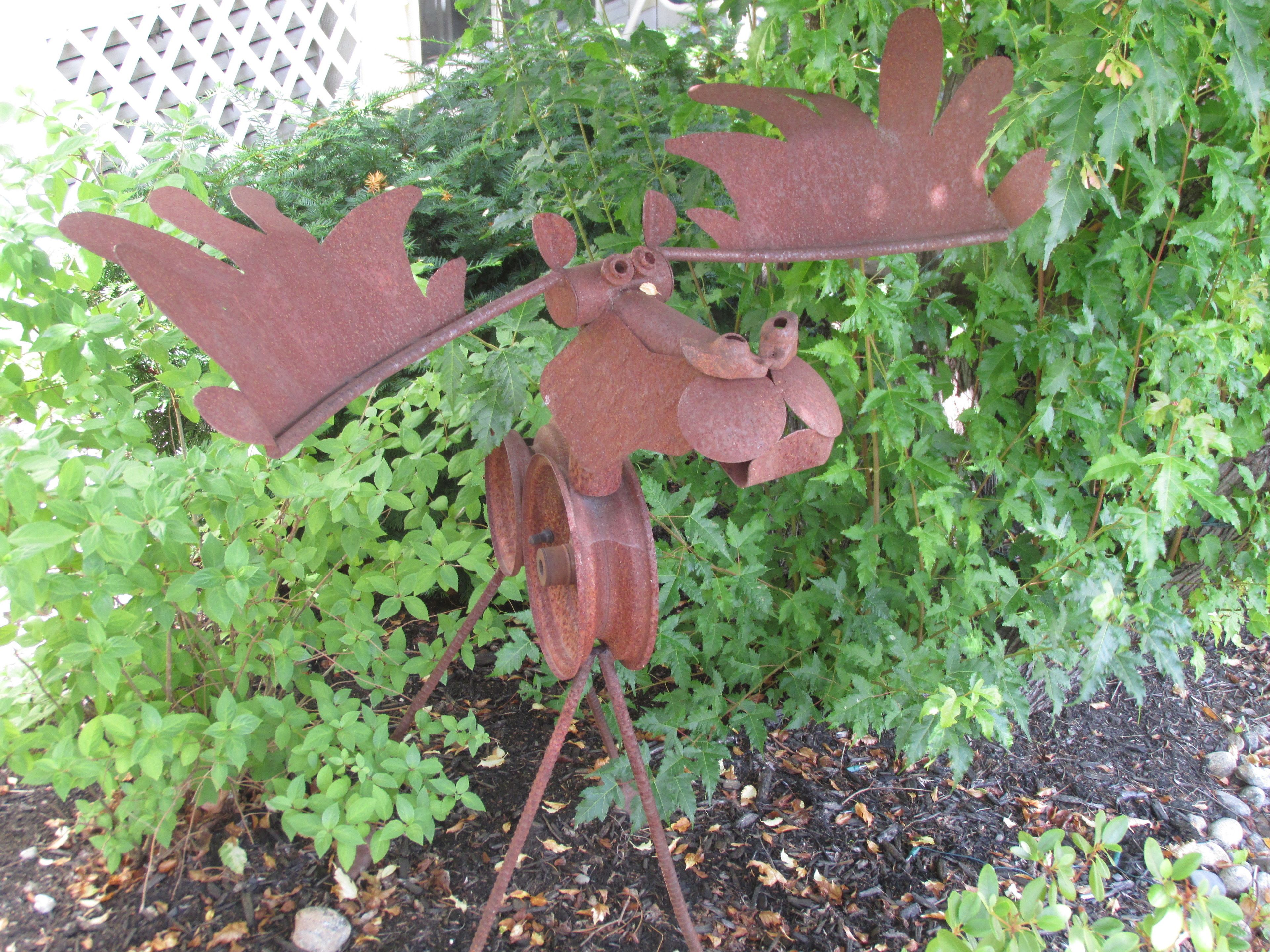 Escultura de metal de un alce con astas en un jardín.