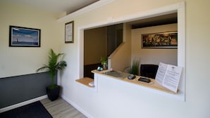 A reception desk with a plant, a framed picture, and a sign.