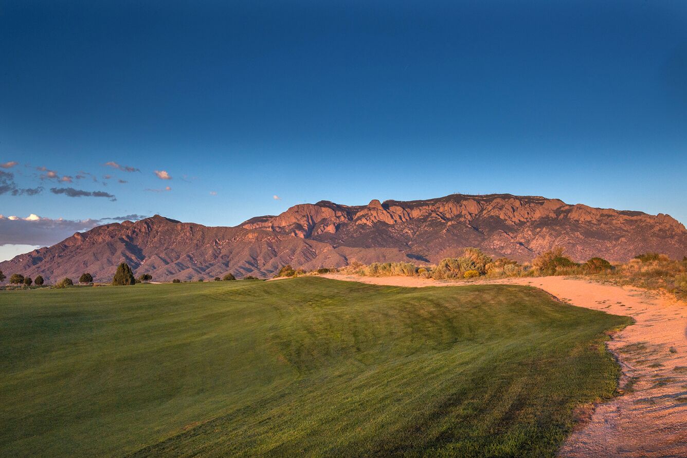 A golf course with a mountain backdrop.