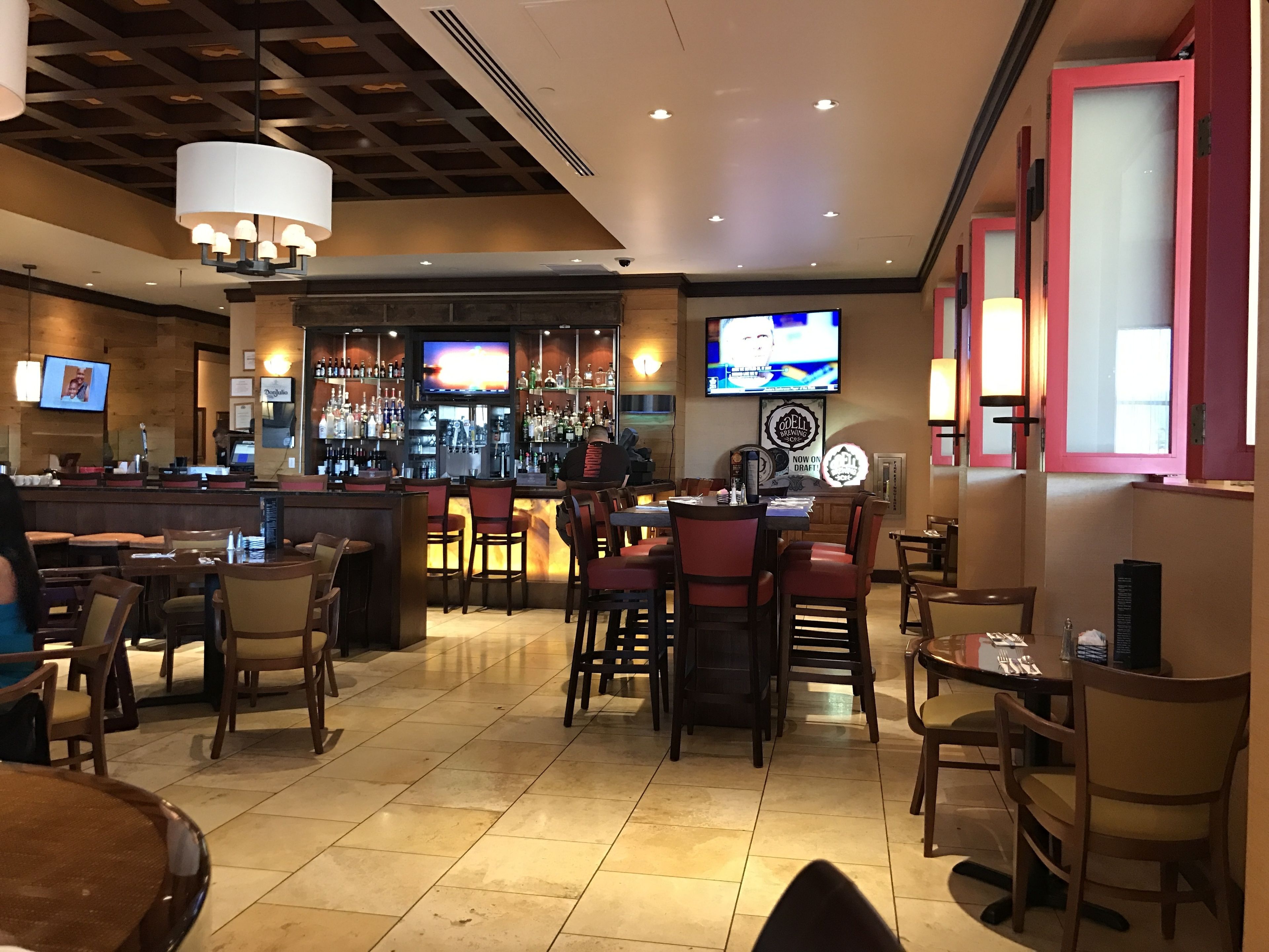A bar area with multiple seating arrangements, a television screen, and a bar counter with various bottles.