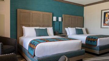 A hotel room with two beds, a chair, and a small table.