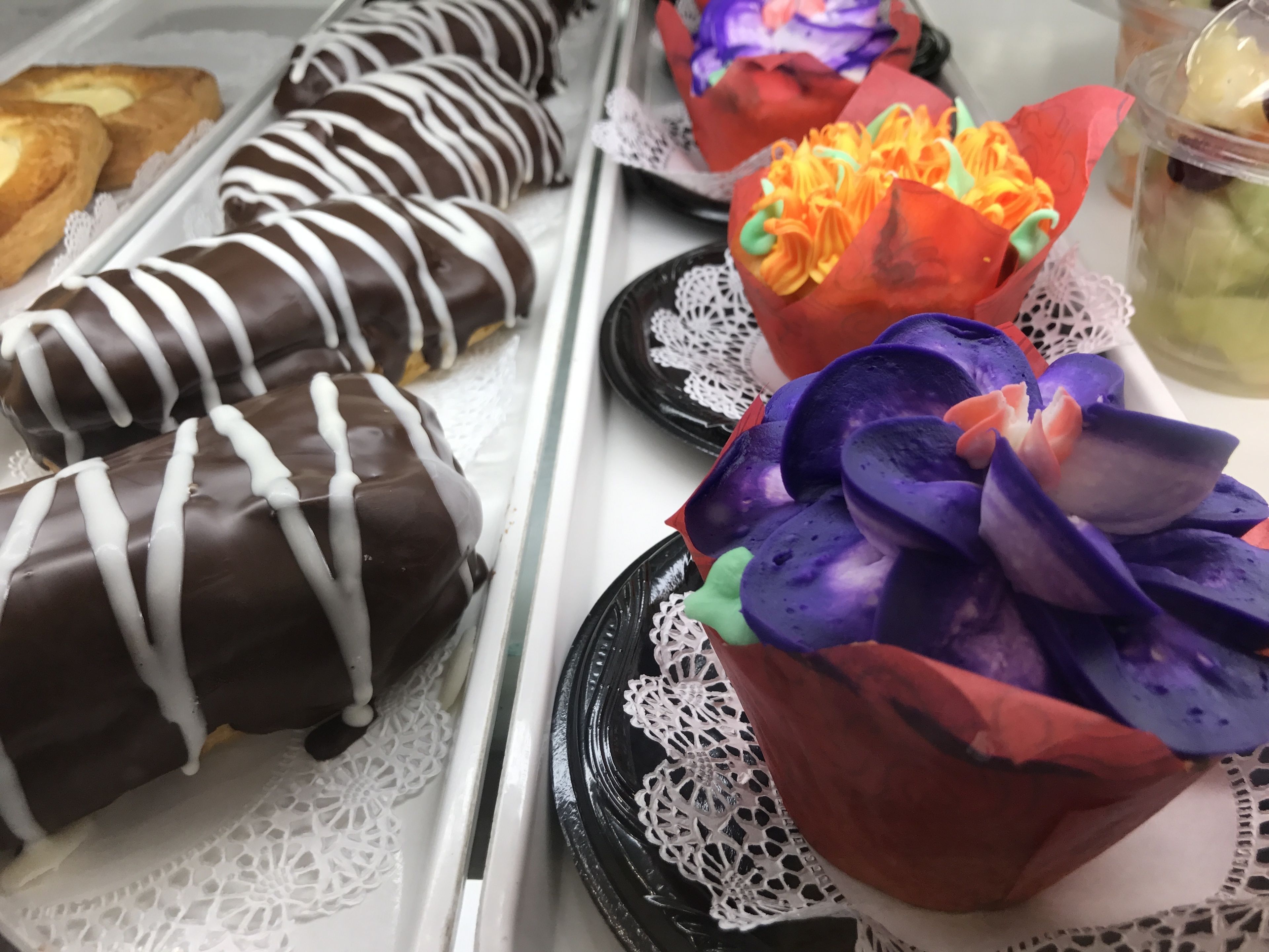 Una bandeja con varios pasteles, incluyendo algunos cubiertos de chocolate y coloridos pasteles decorados.