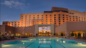 Un hotel con una amplia piscina, varios pisos y un diseño arquitectónico moderno.