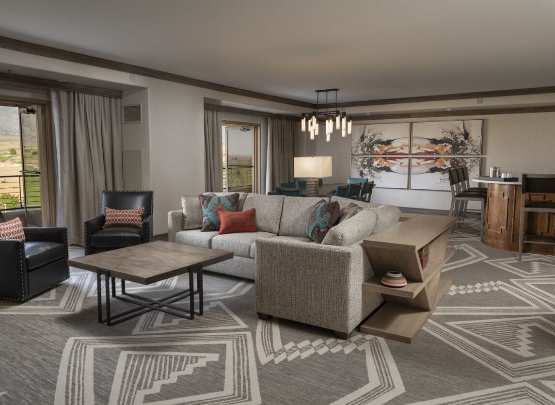 A modern living room with a sofa, armchairs, a coffee table, and a dining area with a lamp.