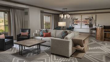 A modern living room with a sofa, armchairs, a coffee table, and a dining area with a lamp.