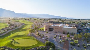 Un campo de golf con club house y zona de estacionamiento.