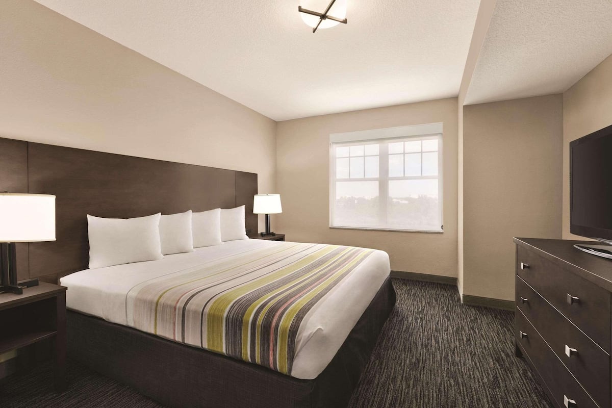 A hotel room with a large bed, two bedside tables with lamps, a dresser, and a television.