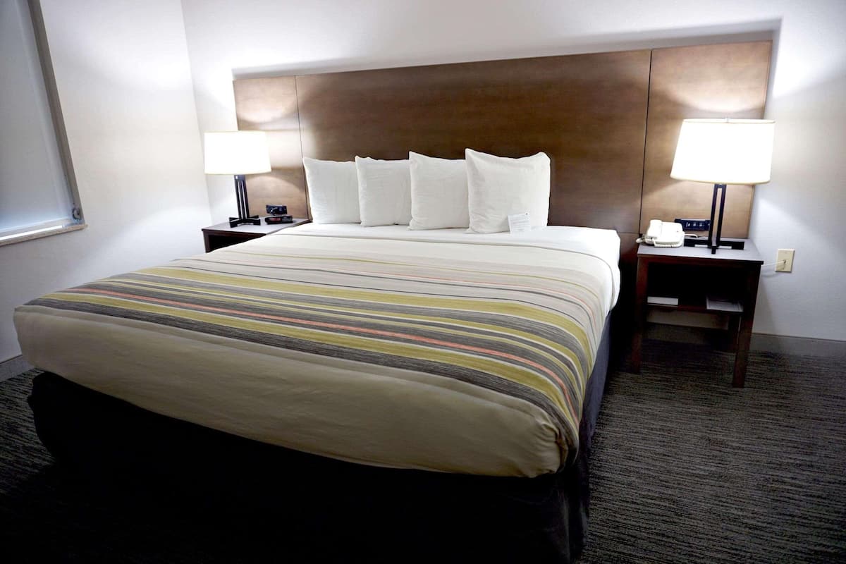 A hotel room with a large bed, two bedside tables with lamps, and a headboard.