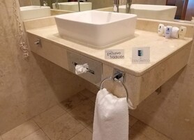 Un baño con lavamanos blanco, toallero y caja de pañuelos.