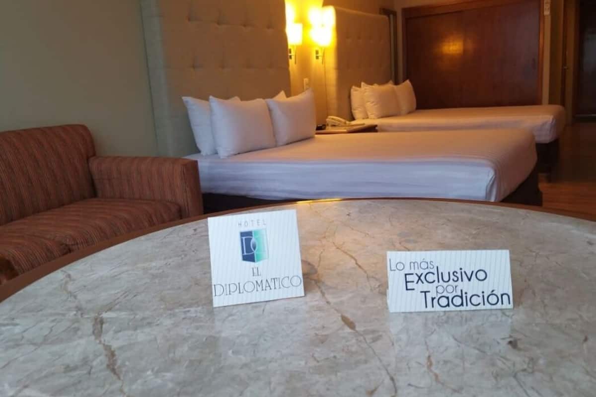 Una habitación de hotel con una cama, un sofá y dos letreros sobre la mesa.