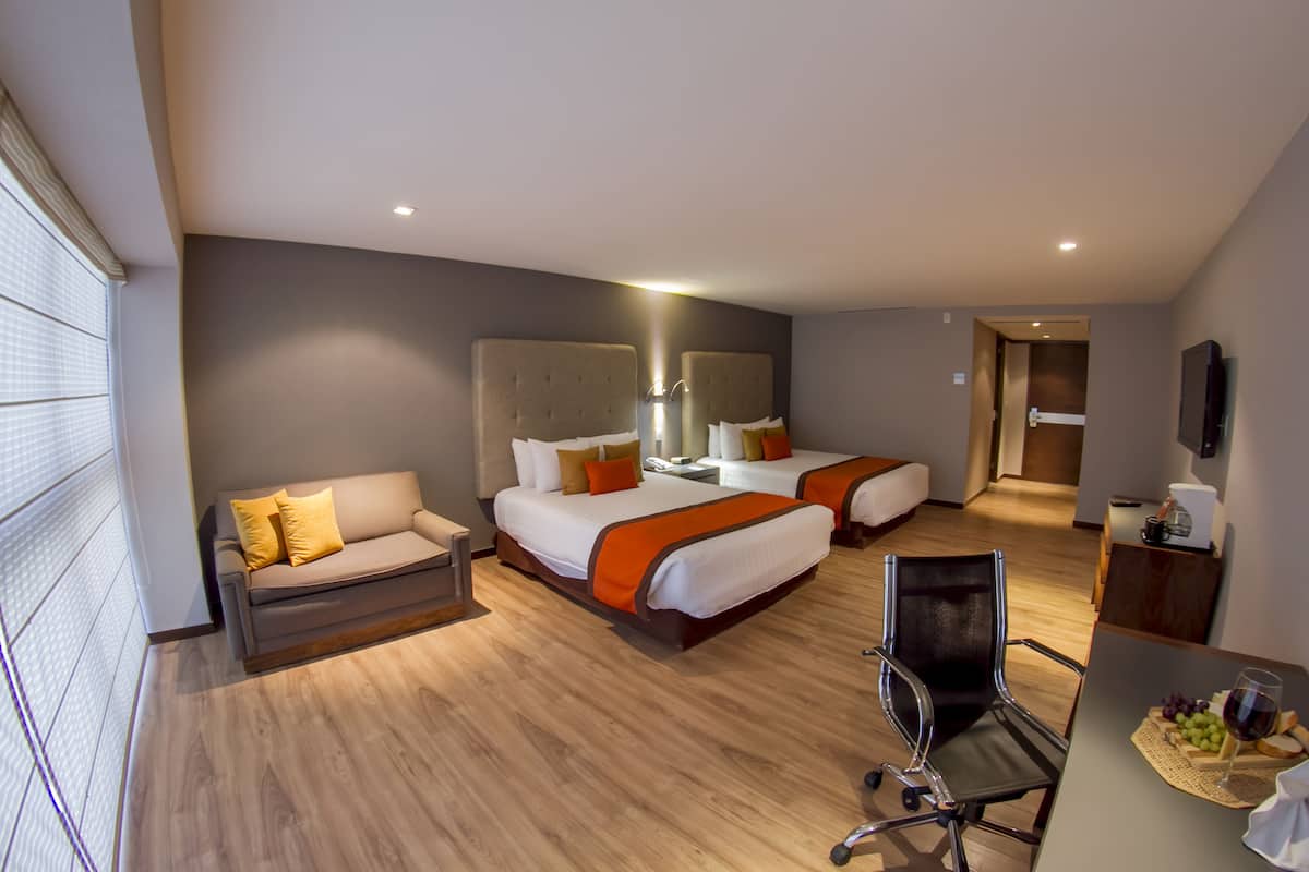 Una habitación de hotel con dos camas, un sofá, un escritorio y una silla.