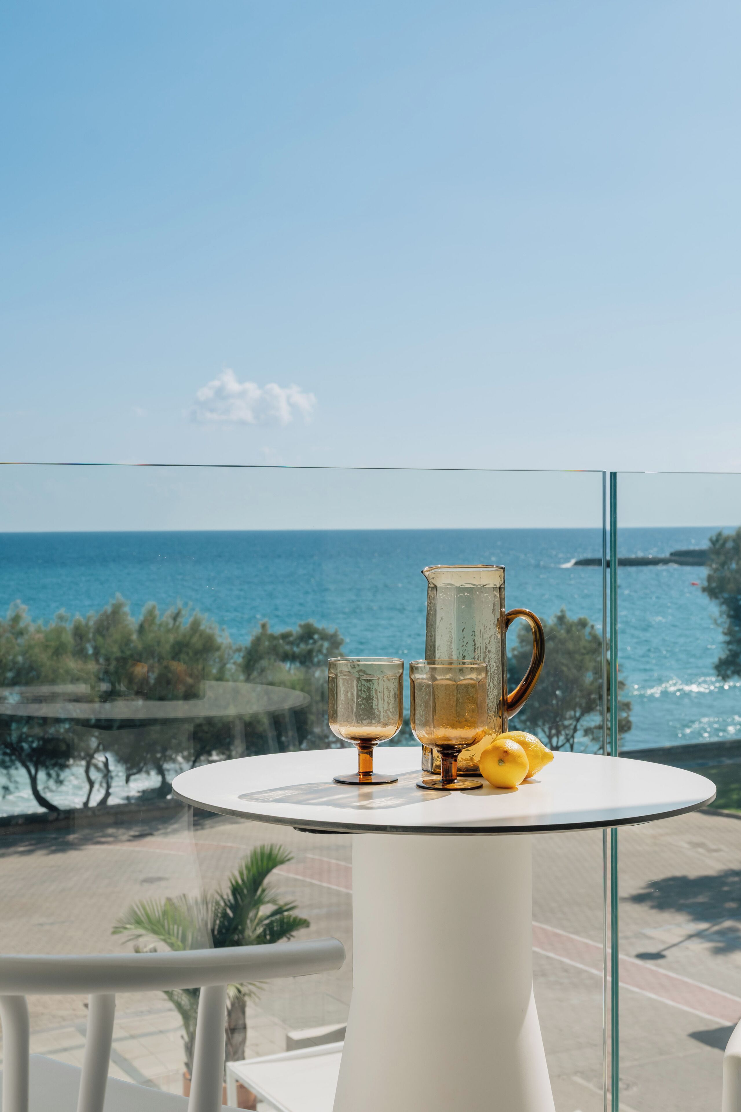 Una mesa con una jofaina y vasos, limones y vista al mar.