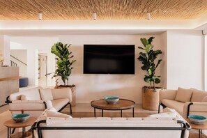 A modern living room with a flat-screen TV, two potted plants, a sofa, and a coffee table. - MIM Mallorca Member of Meliá Collection (Sant Llorenc des Cardassar)