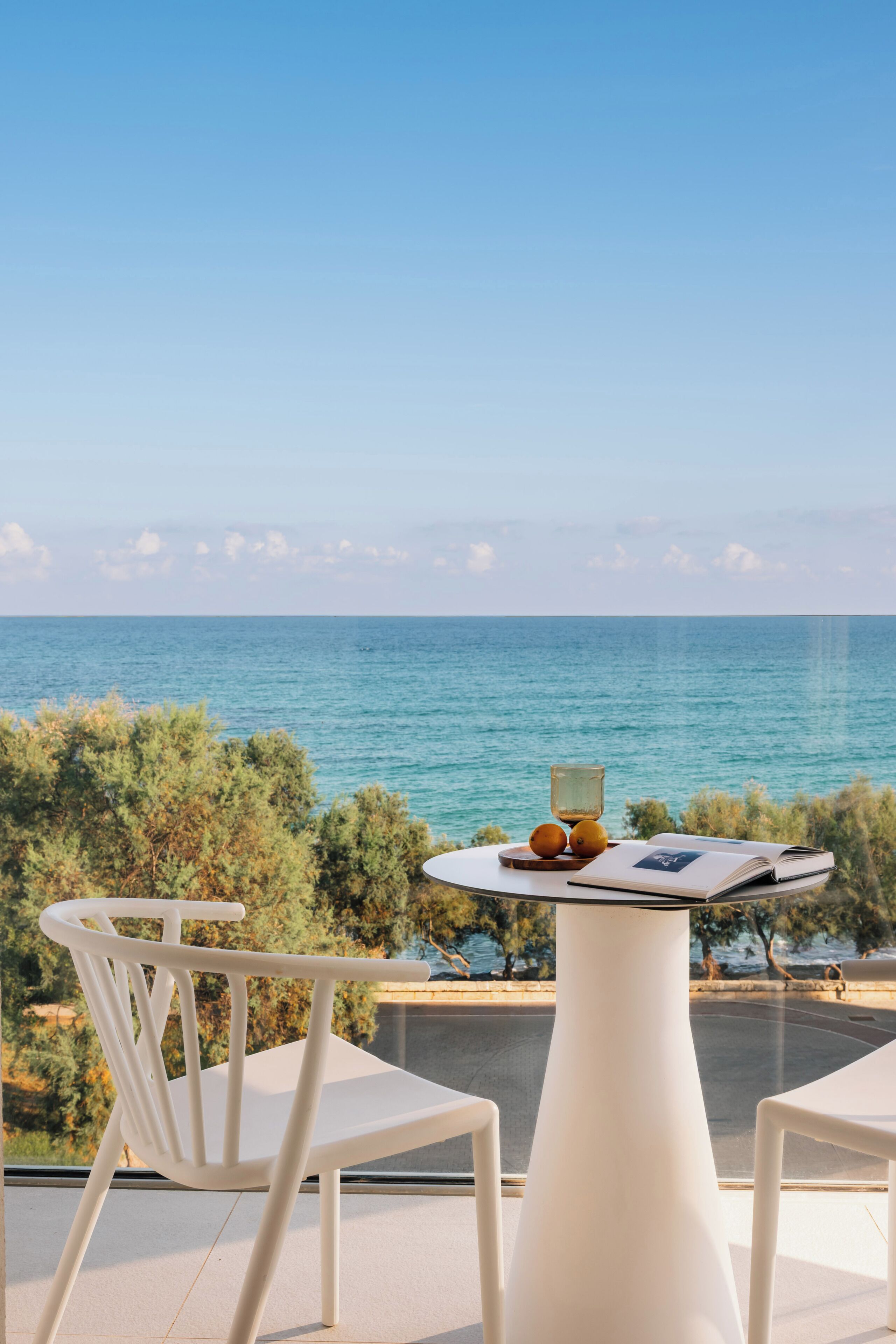 A terrace with a table and chairs, overlooking a body of water.