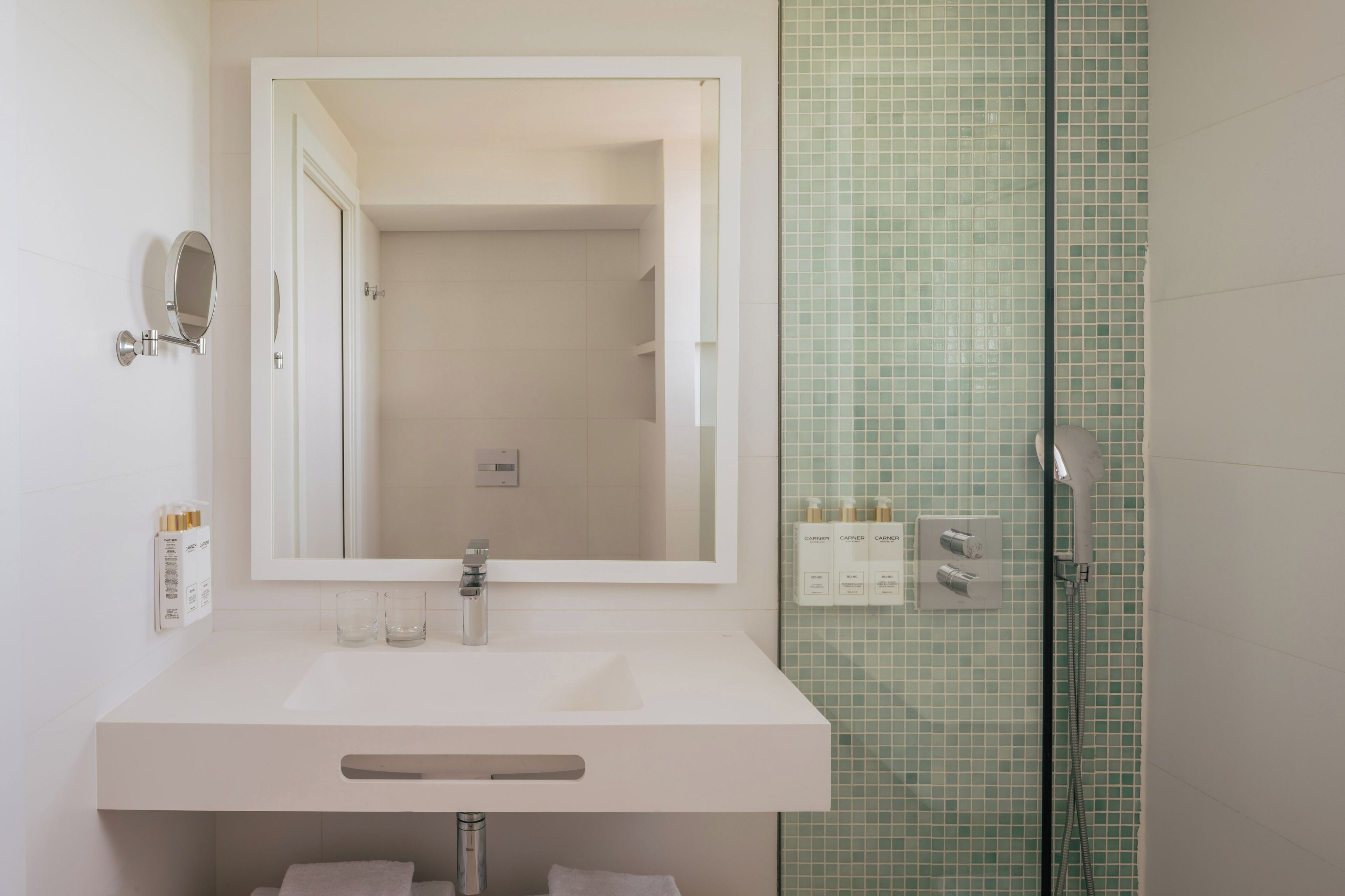 A bathroom with a white sink, mirror, and shower.