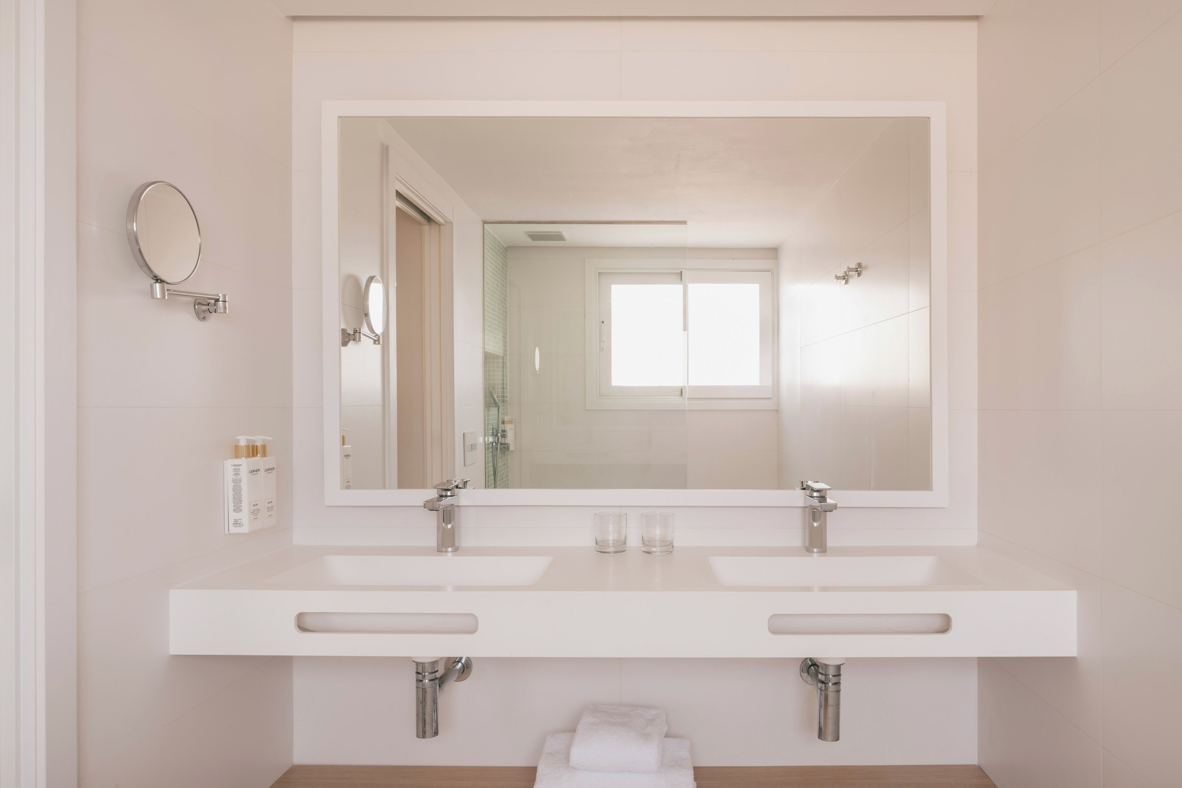 A bathroom with two sinks, a large mirror, and a towel rack.
