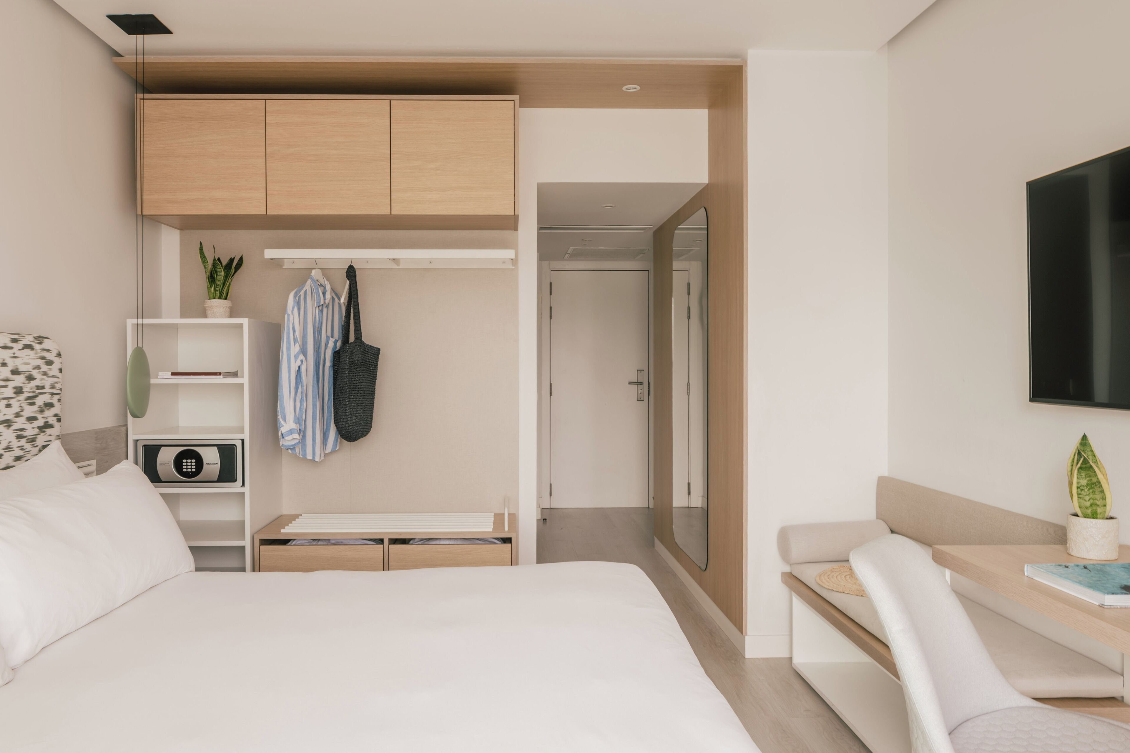 Un dormitorio moderno con cama, escritorio, armario y espejo.