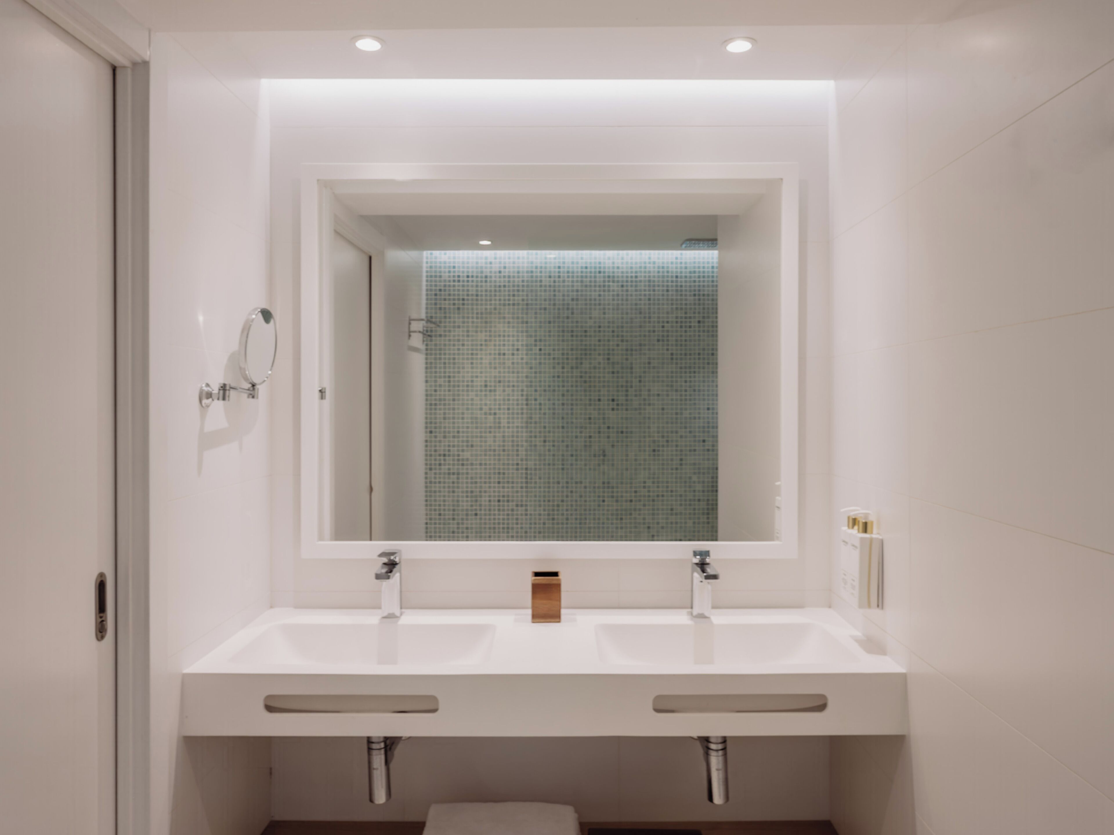 Un baño moderno con un espejo grande, dos lavamanos y una zona de ducha.
