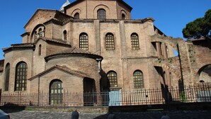 Um edifício histórico com janelas em arco e fachada de tijolos.