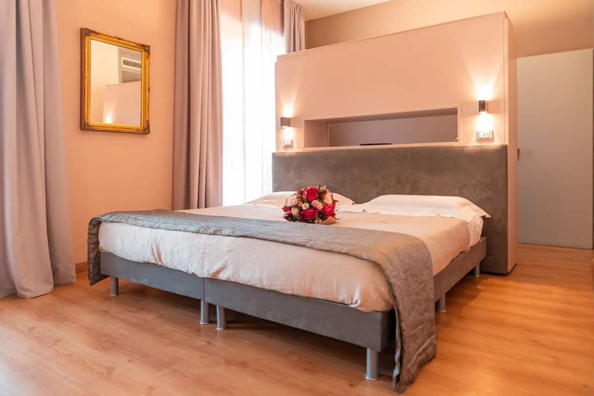 A modern bedroom with a large bed, a headboard with integrated lighting, and a bedside table.
