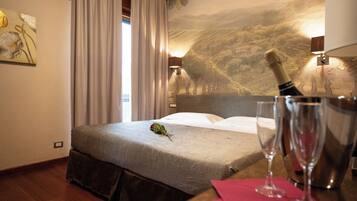 Una camera d'hotel con un letto, una bottiglia di champagne e due bicchieri su un tavolo.