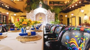 Comedor con mesas dispuestas para una comida, con individuales tejidos y servilletas azules.