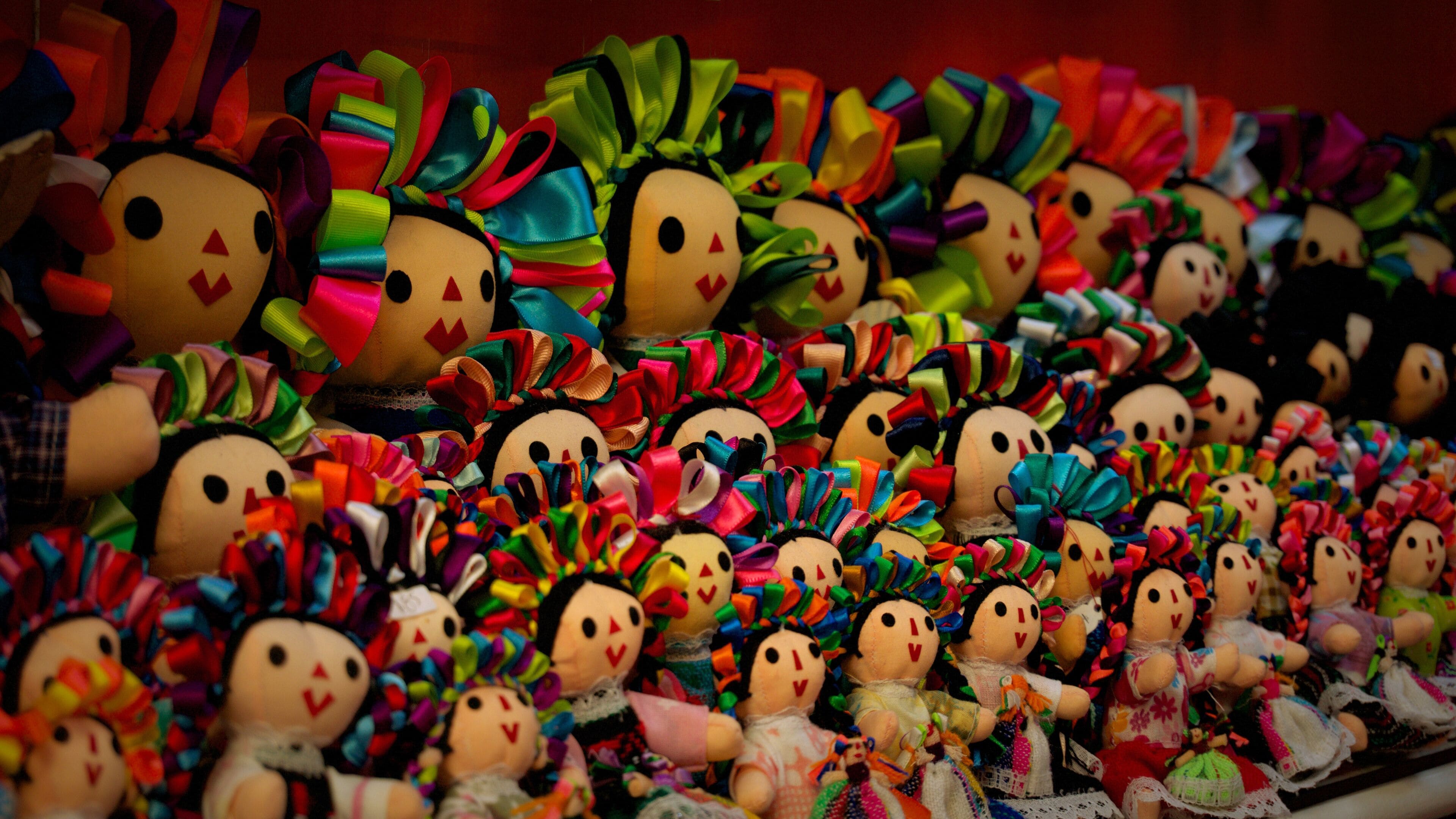 A display of various dolls with colorful ribbons and bows.