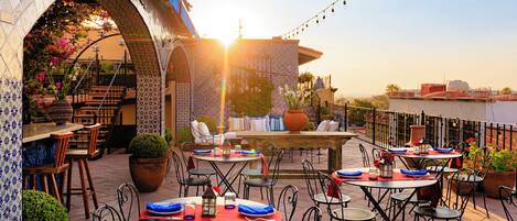An outdoor patio with tables and chairs, a tiled archway, and string lights.