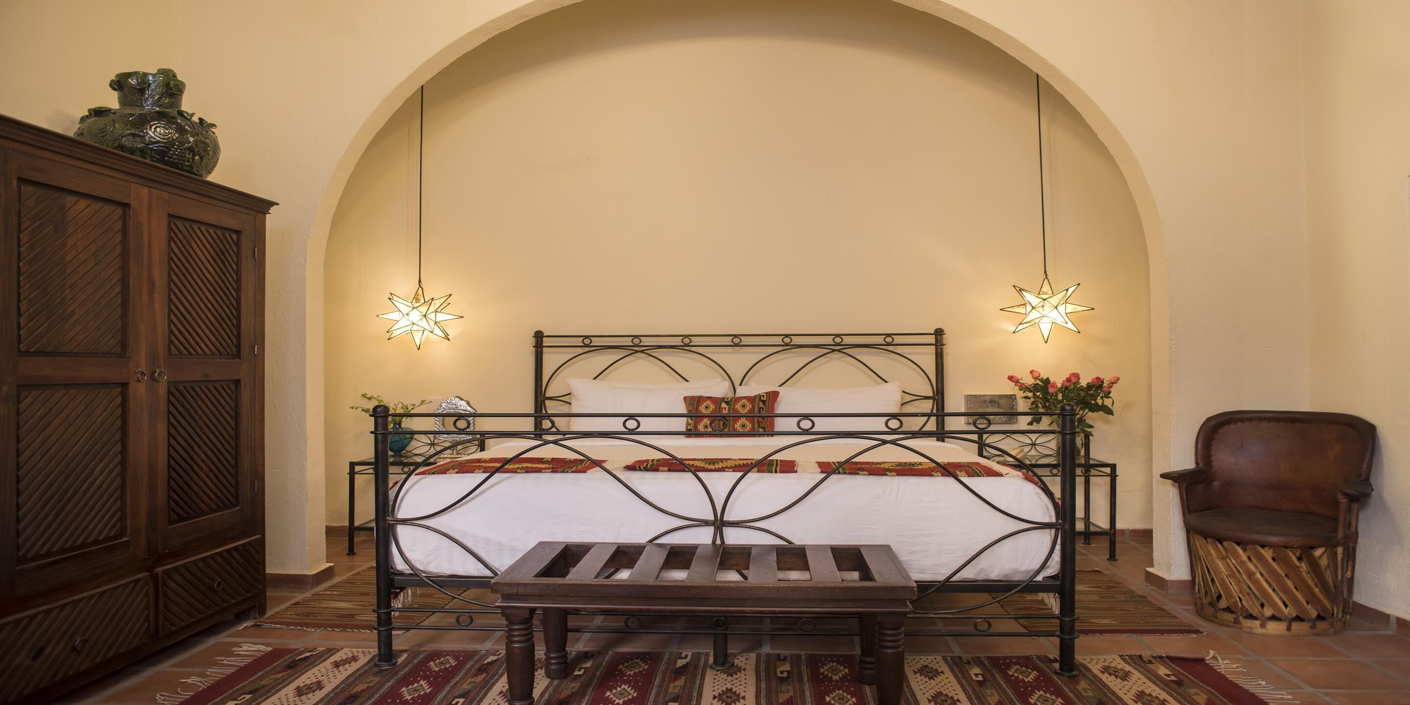 Un dormitorio con una cama, un armario de madera, un banco y una silla.