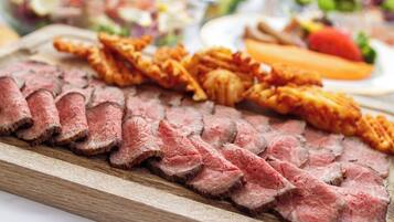 A wooden cutting board with sliced meat and fried items.