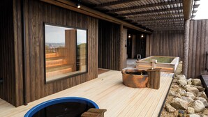 A wooden deck with a hot tub, a wooden sauna, and a large window overlooking a landscape. - Okayama International Hotel (Okayama)