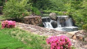 A waterfall cascading over rocks, surrounded by lush greenery and pink flowering bushes. - Okayama International Hotel (Okayama)