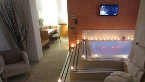 Un moderno spa con una bañera grande, un sofá, un escritorio y un televisor en la pared.