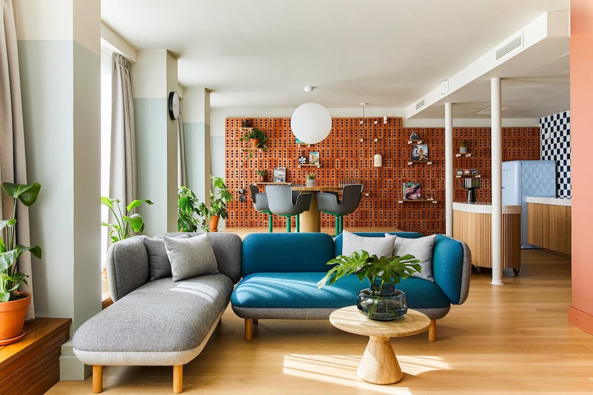 A modern living room with a sectional sofa, a round coffee table, and a kitchen in the background.