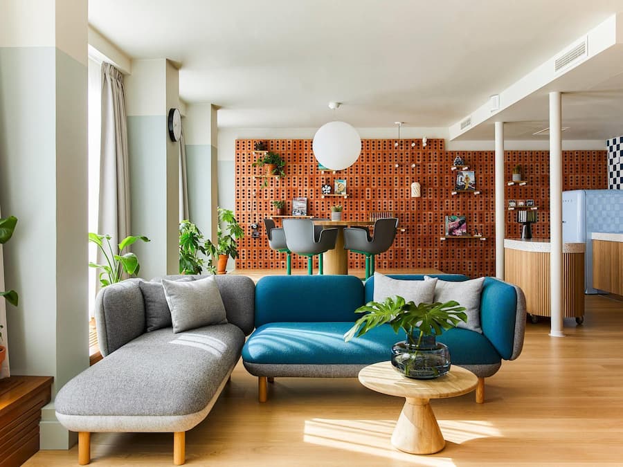 Una sala de estar moderna con un sofá seccional, una mesa de centro redonda y una cocina al fondo.